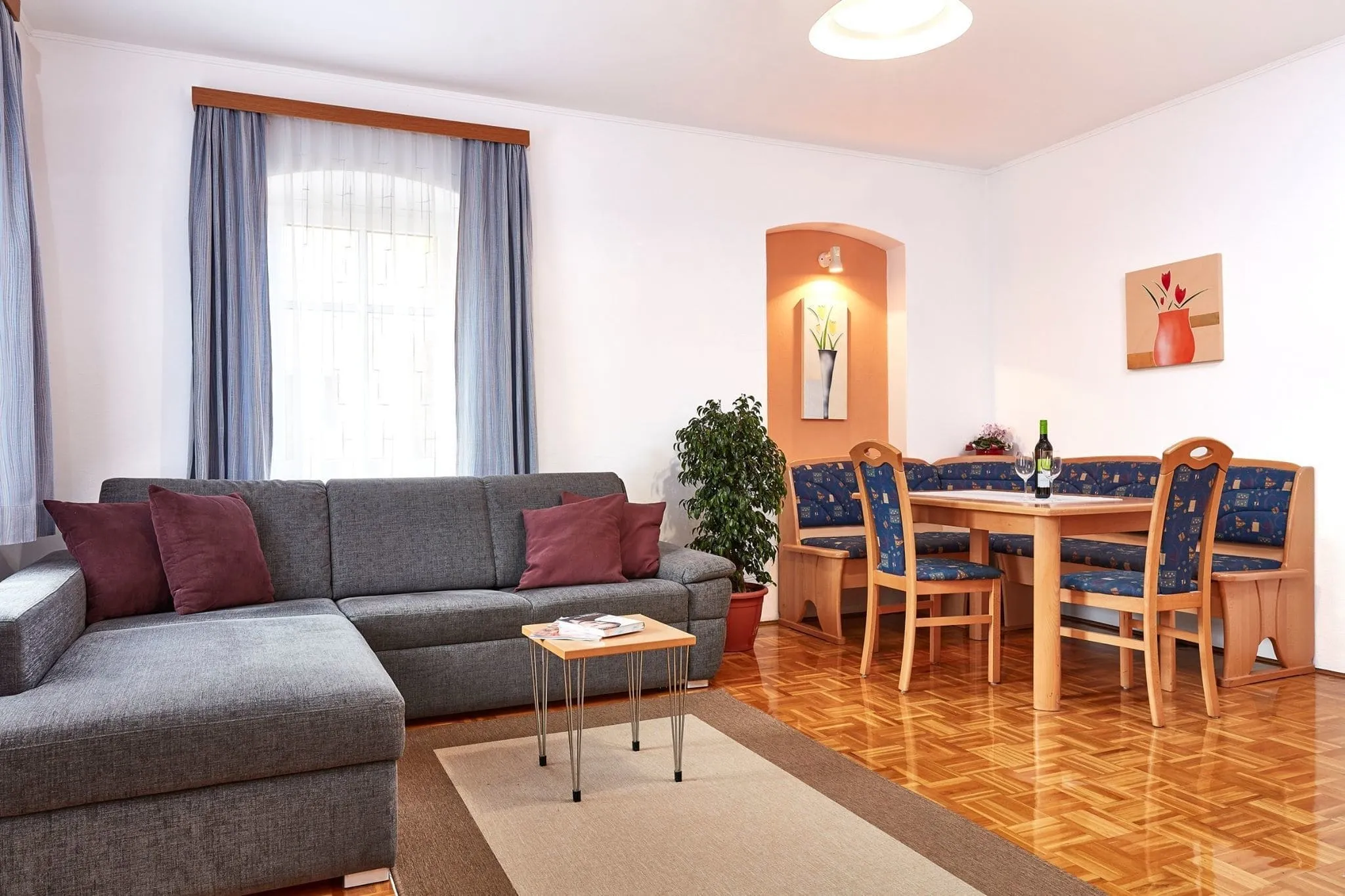 Wohnraum der Ferienwohnung Eins mit Eckcouch, Couchtisch und Essecke aus Holz