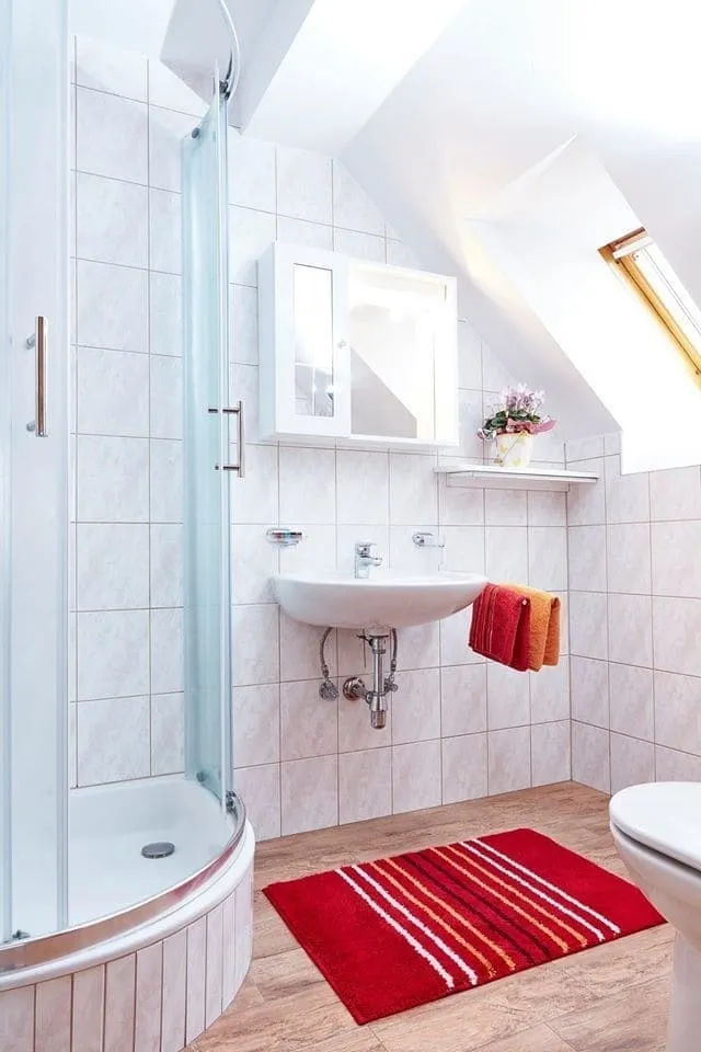 Badezimmer der Ferienwohnung Vier mit Eckdusche, Waschbecken und Dachfenster